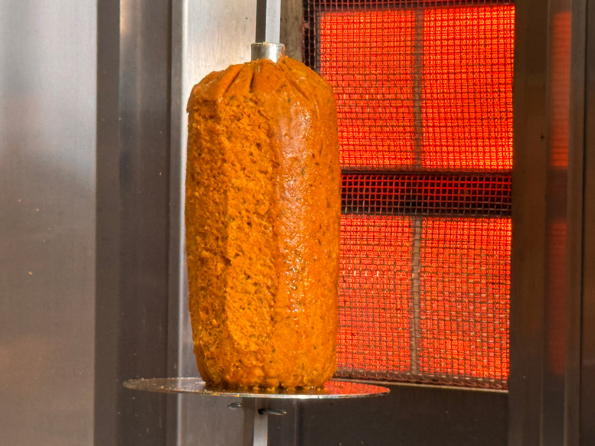 Veganer Dönerspieß von JACK's senkrecht am Grill, außen goldbraun gebraten