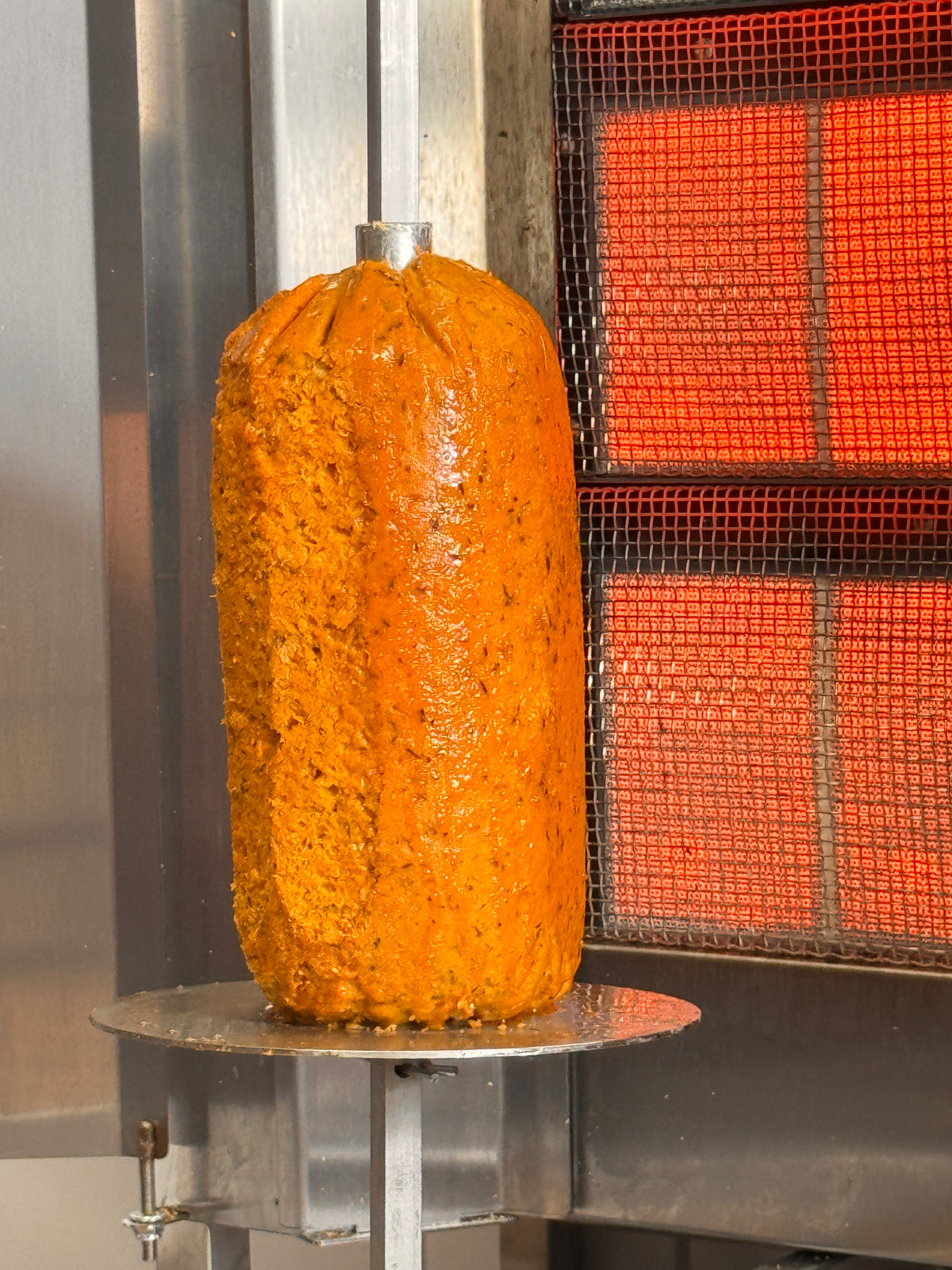 Veganer Drehspieß aus Erbsenprotein waagerecht am Grill mit knuspriger Oberfläche